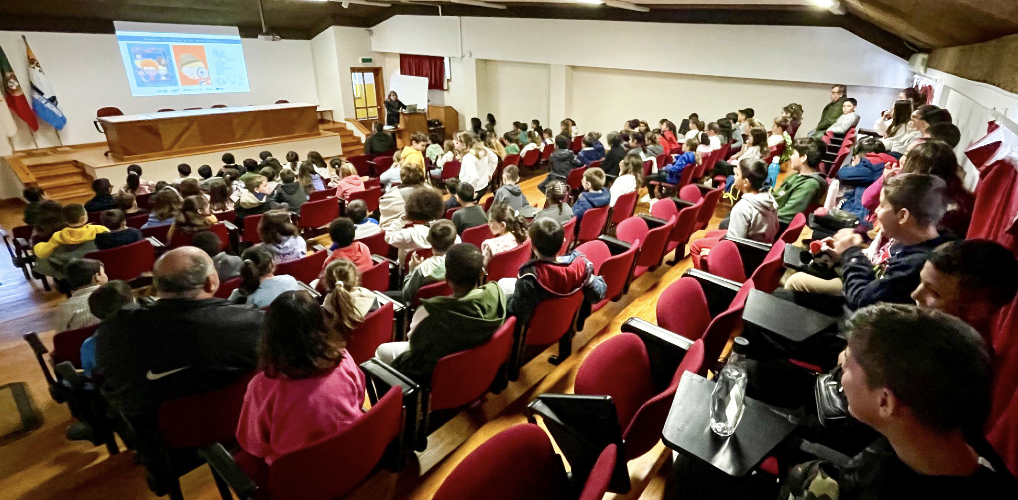 jovens alunos em auditório a ouvir orador 
