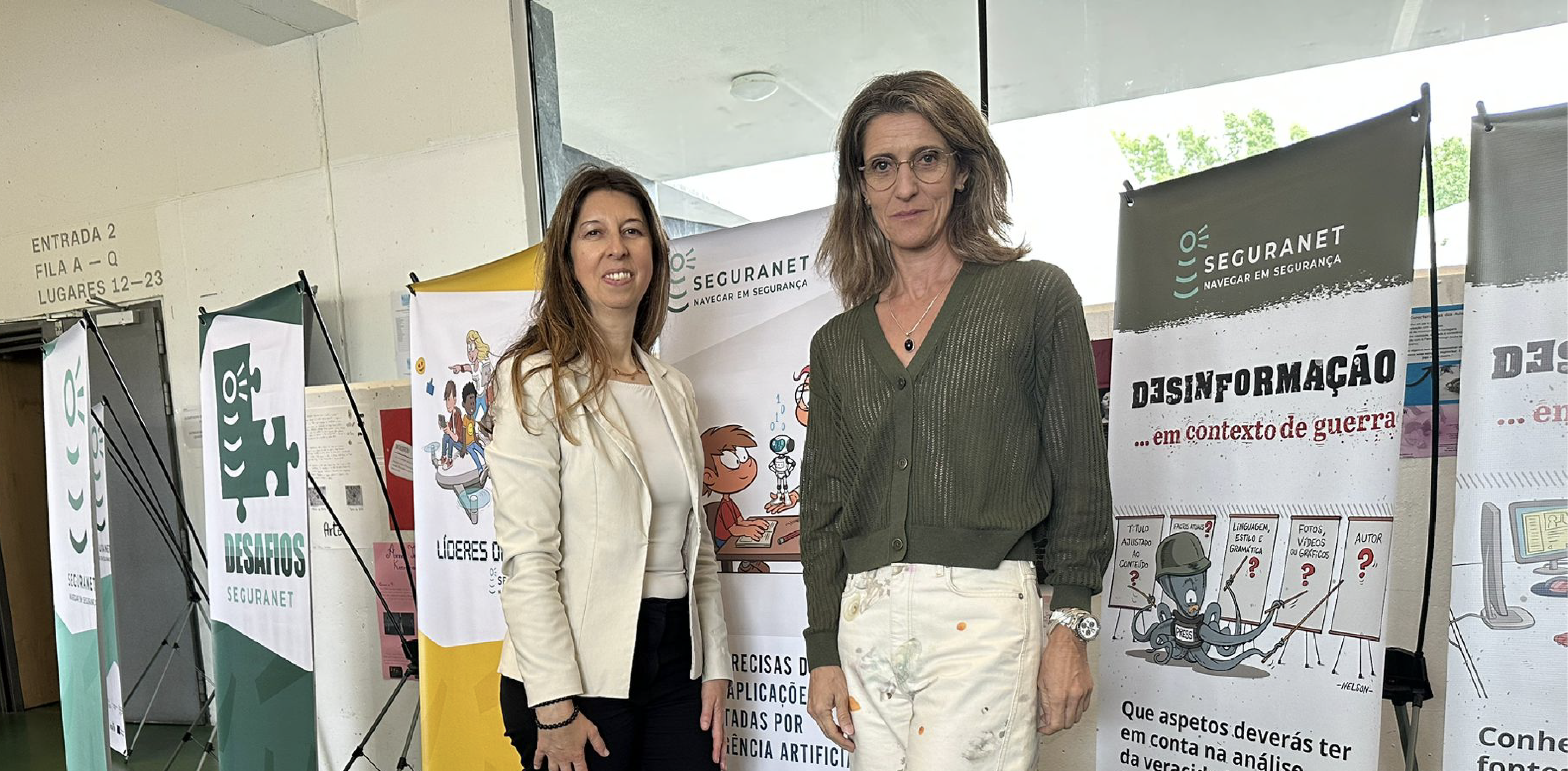 duas mulheres junto a vários roll ups num evento