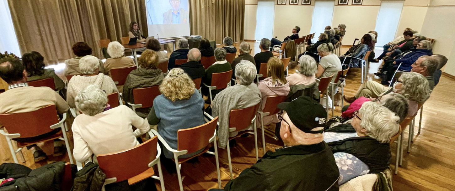 adultos mais velhos numa sala a ouvir um orador